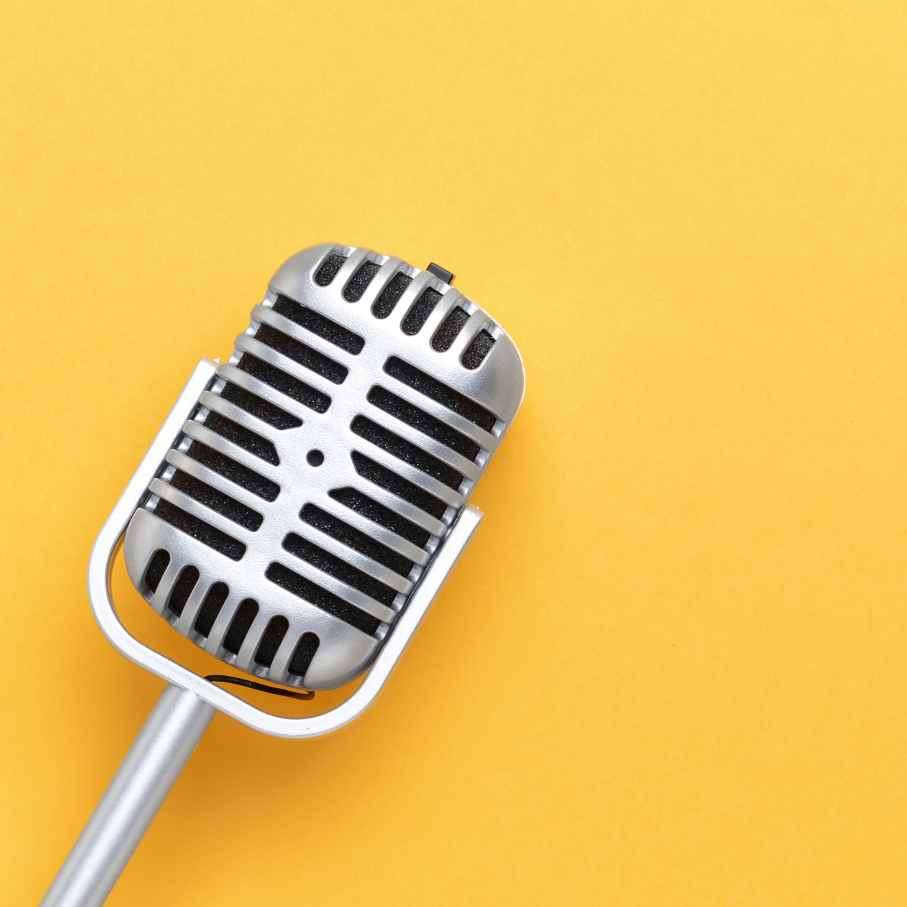 Strategic brand positioning and messaging services that define identity and drive engagement. Vintage microphone against a bright yellow backdrop, representing brand voice development that turns heads and creates emotional audience connection.