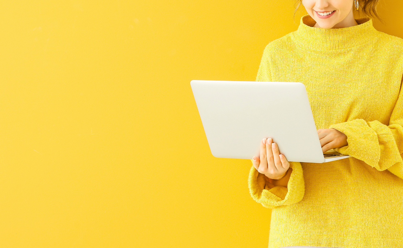 Person holding laptop against a bright yellow background representing automated lead nurture sequences that guide prospects through the sales funnel.