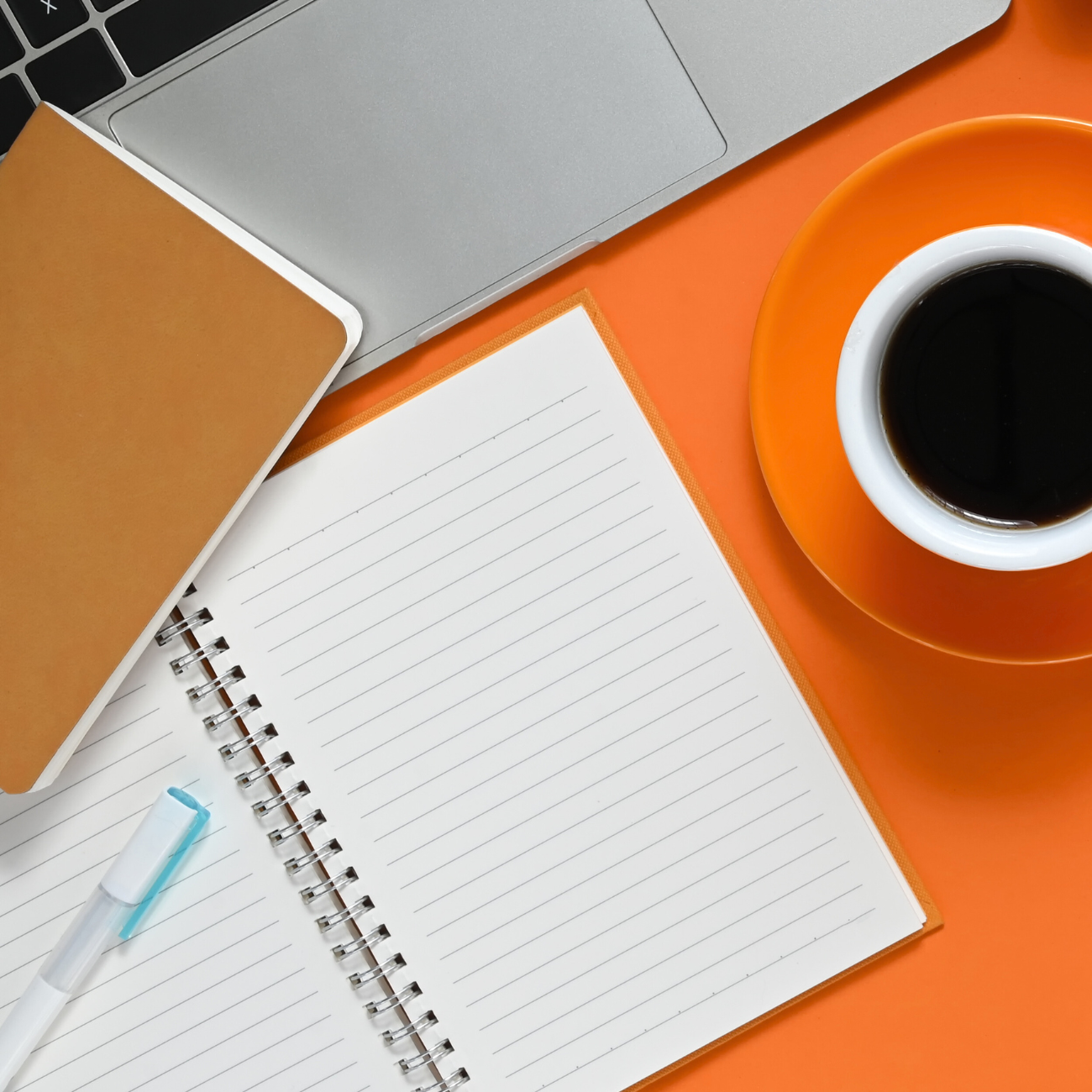 Flat lay of a workspace with notebook, pen, and laptop symbolizing customer onboarding emails that activate new users and build retention.