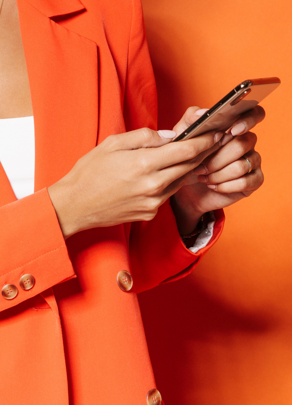 Person Holding Smartphone – Magtyne Digital Communication Visual Person wearing orange jacket holding smartphone against bright background