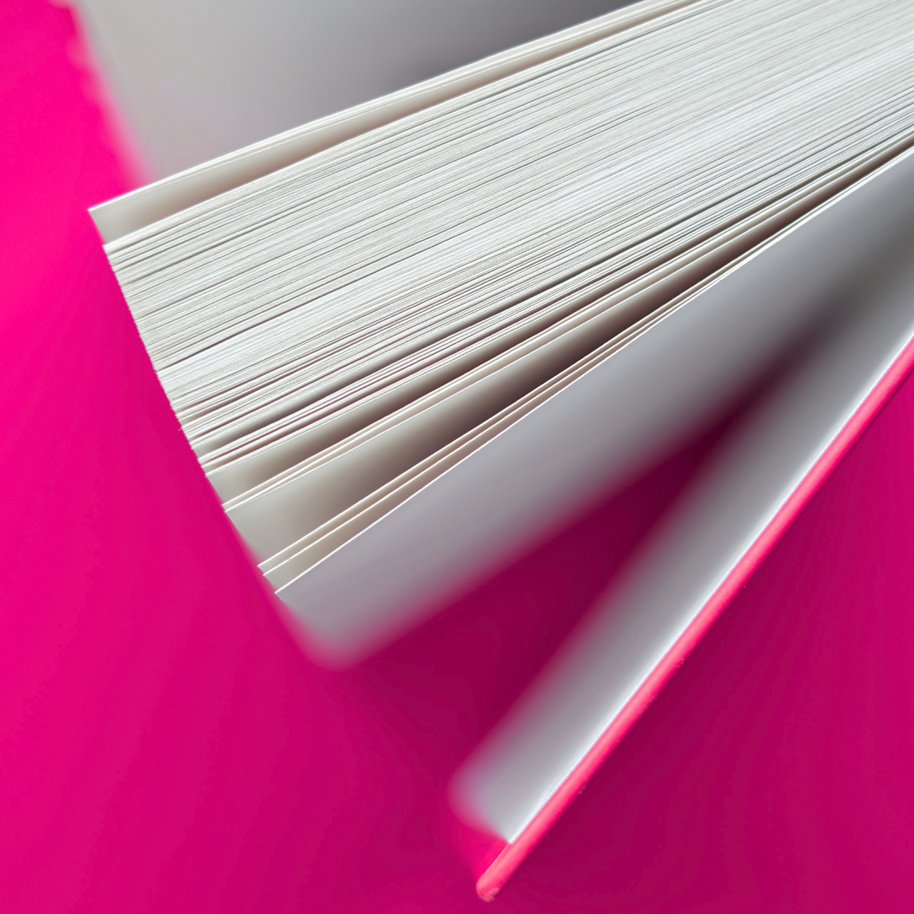 Fanned Book Pages on Pink – Magtyne Knowledge and Strategy Visual Open book pages fanned out against pink background