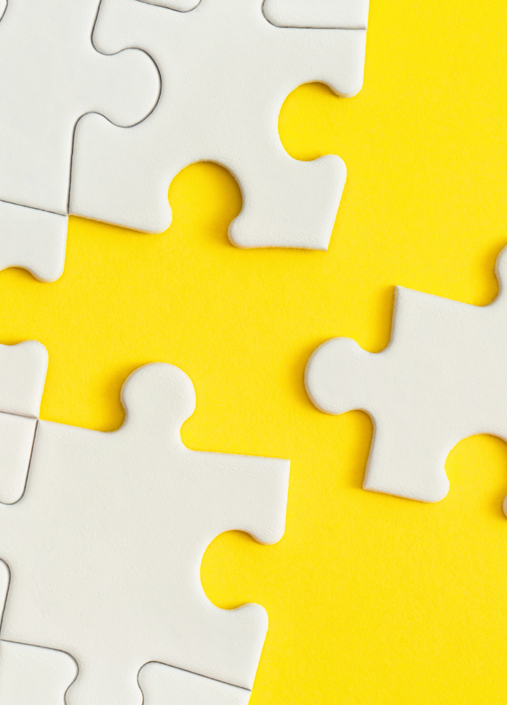 magtyne image_yellow bg-white puzzle pieces Person wearing orange jacket holding smartphone against bright background